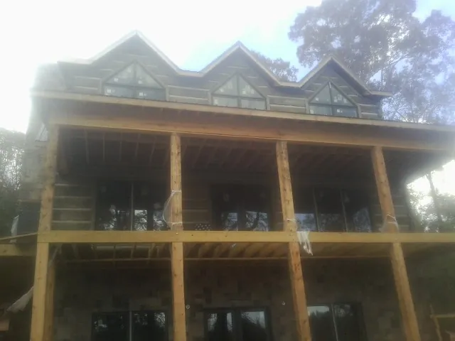 Dormers and porch framing on a large log home under construction — Roof Coating work by our crew in Carencro