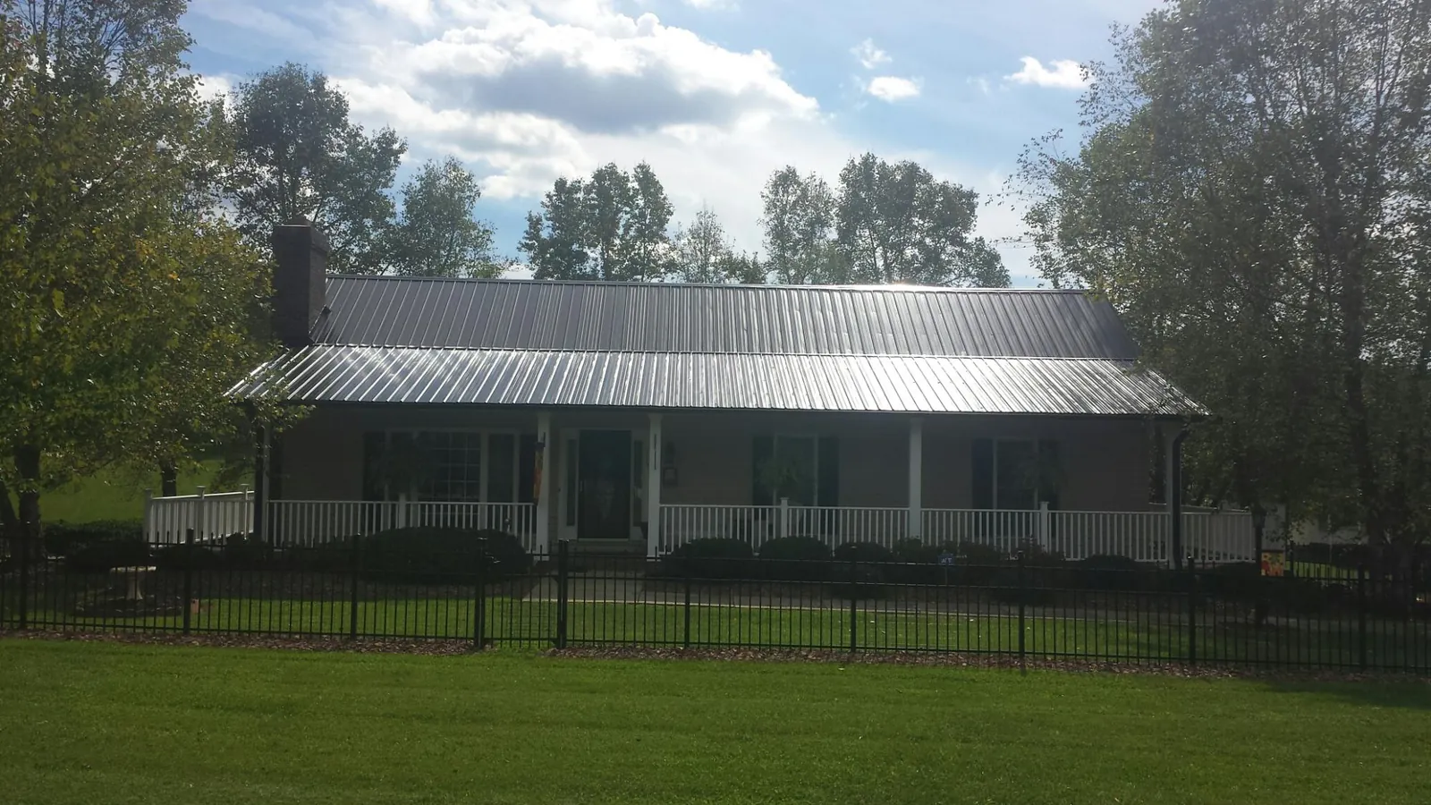 Gray metal roof on a brick ranch with a full width front porch — Gutter Guard Installation work by our crew in Carencro