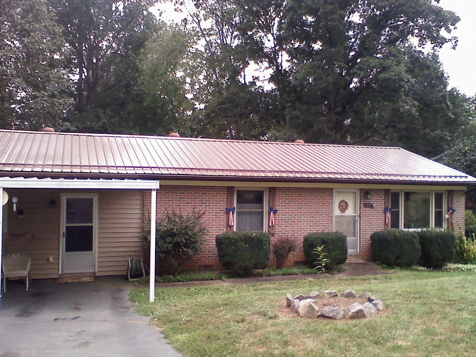 Bronze metal roof and carport on a brick ranch home — Roof Repair work by our crew in Carencro