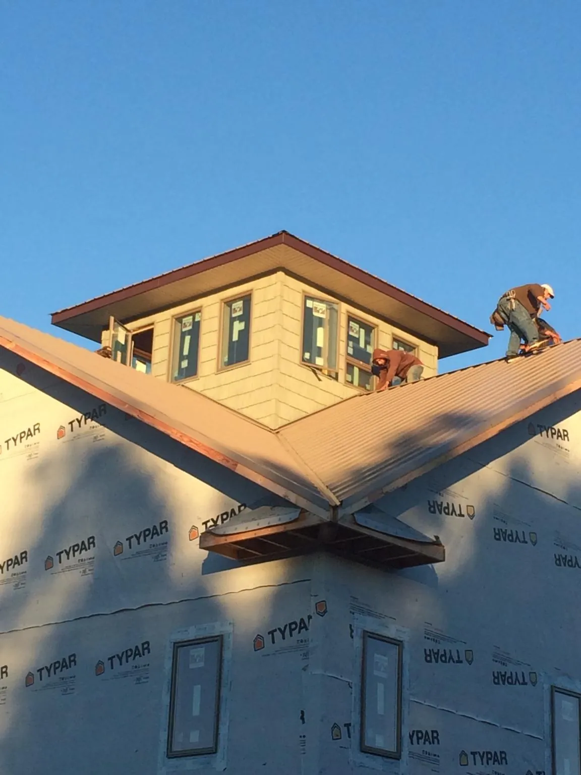 Roofers working around a rooftop cupola on a new metal roof at sunset — Roof Waterproofing in Carencro by Roofing Brothers